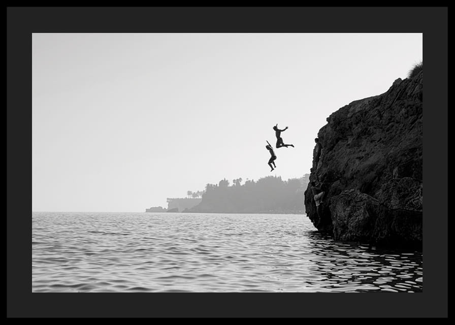 Sort-hvid plakat med et fotografi af to mennesker, der hopper fra en klippe i havet-12