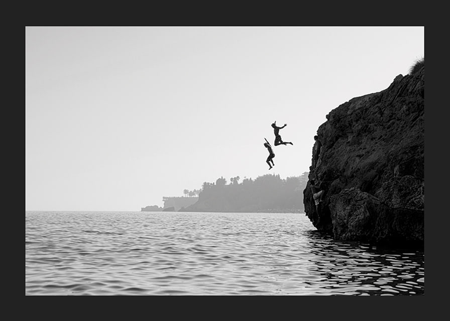 Black and white poster with a photograph of two people jumping from a cliff into the sea-12