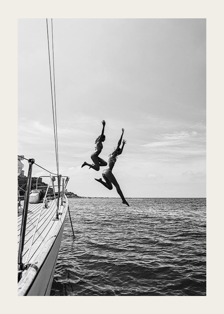 Black and white poster with a photograph of two people jumping from a sailboat into the sea-12