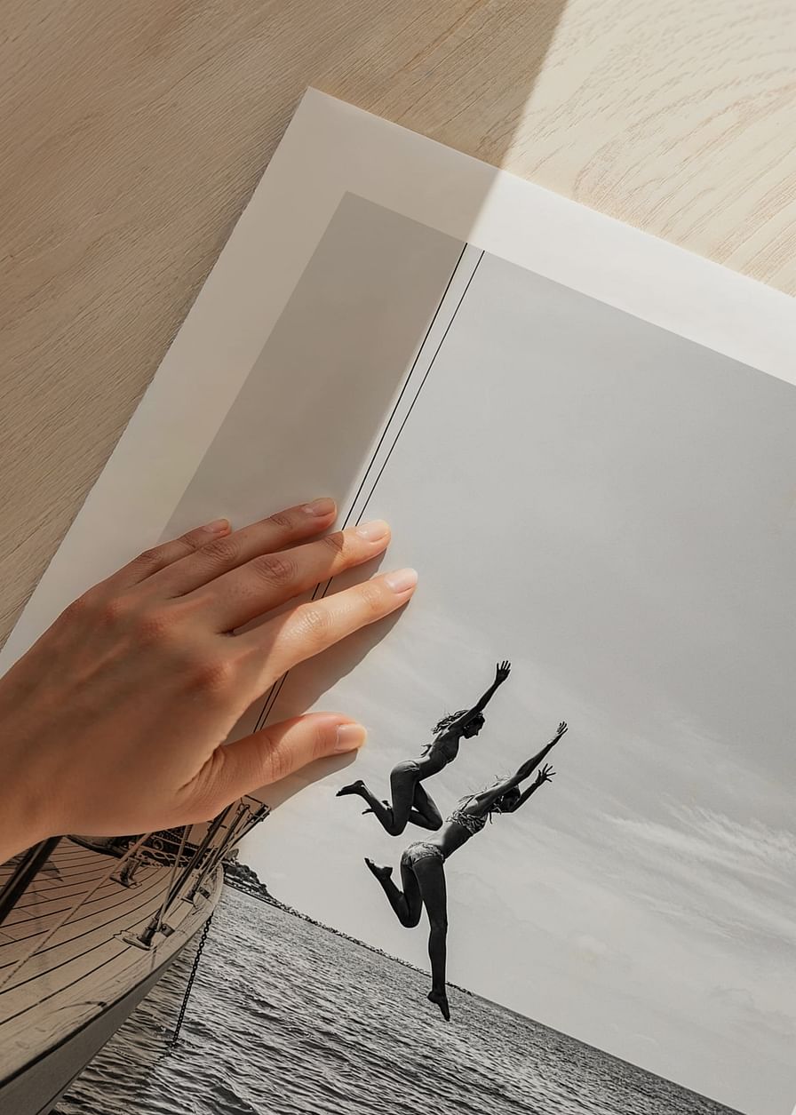 Afiș alb-negru cu o fotografie a doi oameni care sărind de pe o barcă cu pânze în mare-12