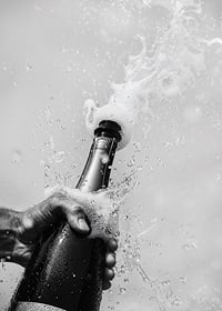 Schwarz-weißes Poster mit einem Foto einer gerade geöffneten Champagnerflasche-7
