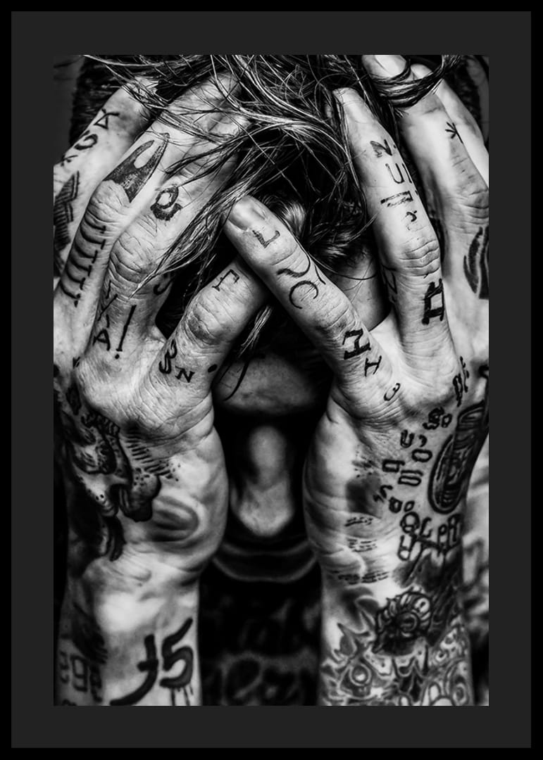 Melnbalts plakāts ar vīrieša fotogrāfiju, kura seja ir paslēpta tetovētajās rokās-12