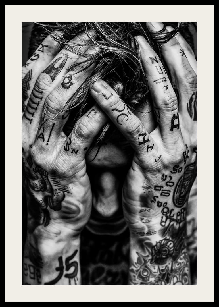 Melnbalts plakāts ar vīrieša fotogrāfiju, kura seja ir paslēpta tetovētajās rokās-12