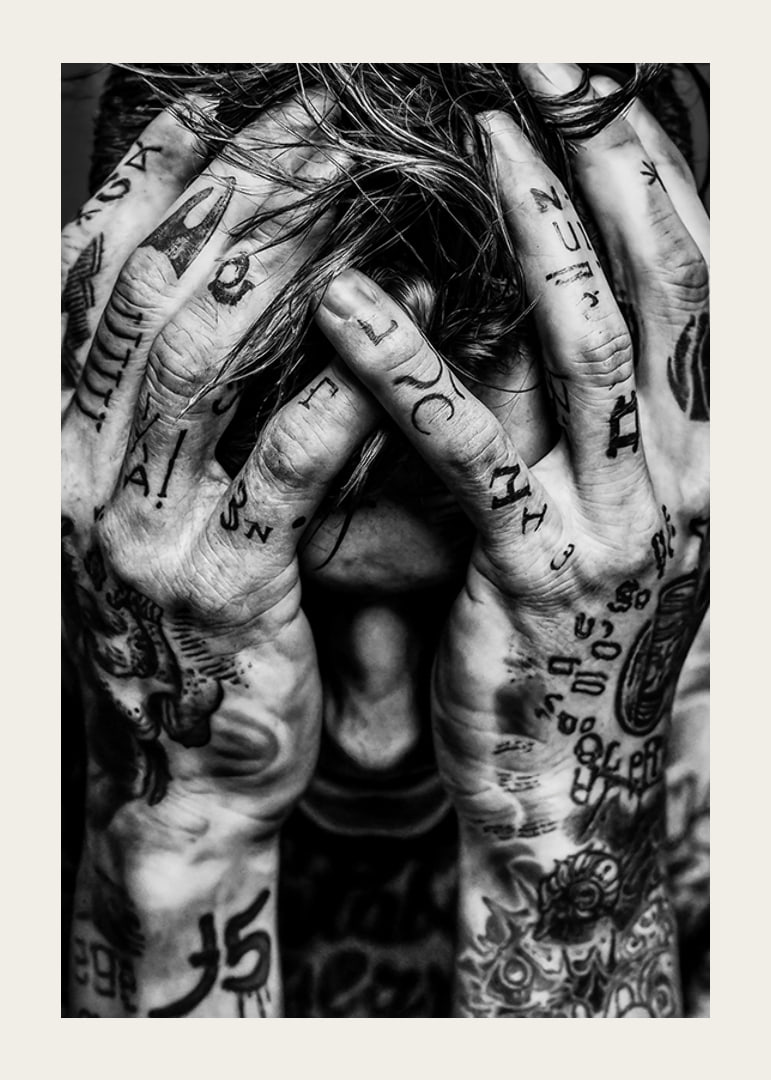 Black and white poster with a photograph of a man with his face hidden in his tattooed hands-12