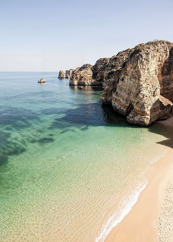 Plakát egy elhagyatott strand és egy kristálytiszta tenger képével egy szikla mellett-12