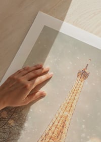 En vinterposter med Eiffeltornet som lyser upp ett snöigt Paris i gyllene sken.-9