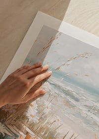 En poster av böcker bland prästkragar vid en solig strand med havets vågor i bakgrunden-9