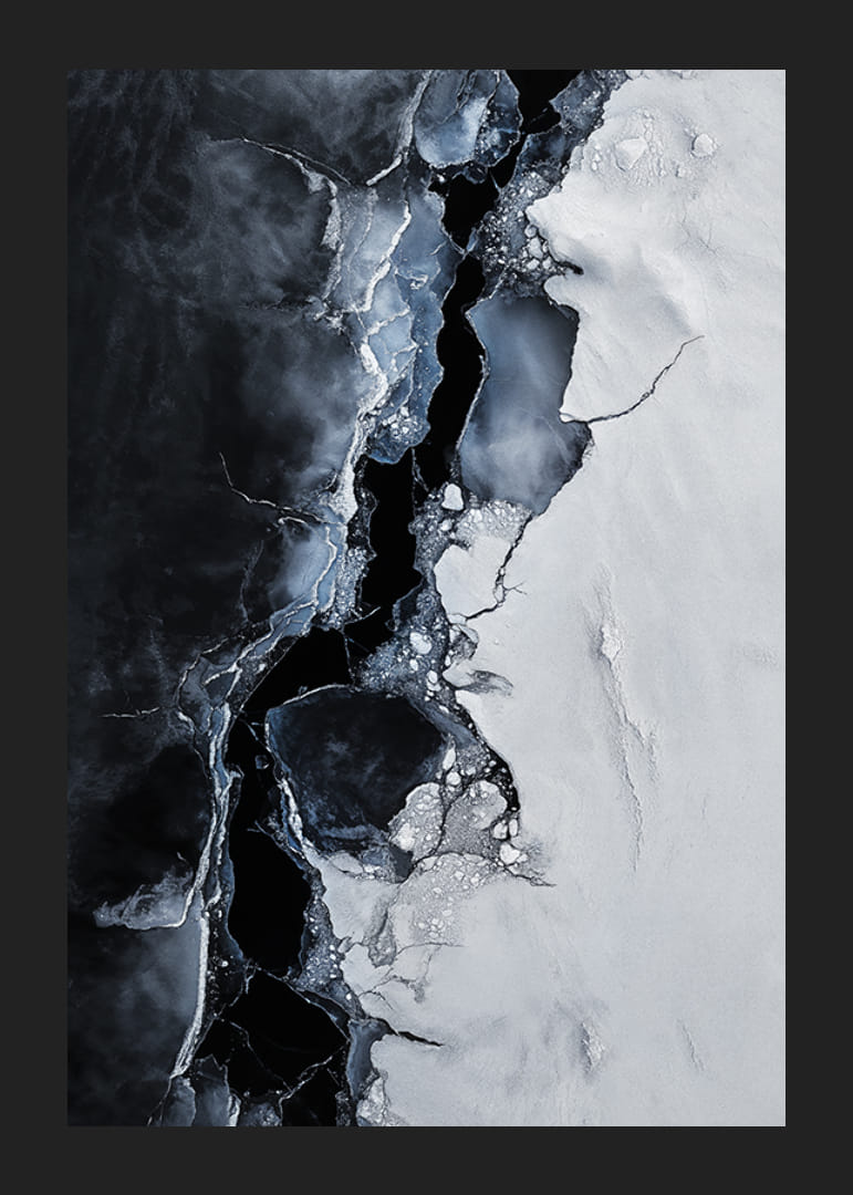Pęknięty lód spotyka się z ciemną wodą, tworząc dramatyczny kontrast, który oddaje surowe piękno zimy-12