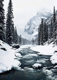 A calm river meanders through a snow-covered forest, surrounded by high mountains and the quiet beauty of winter-7