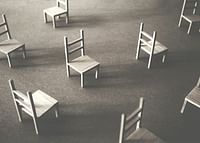O imagine minimalistă a scaunelor goale împrăștiate pe podea, simbolizând liniștea și spațiul de reflecție-3