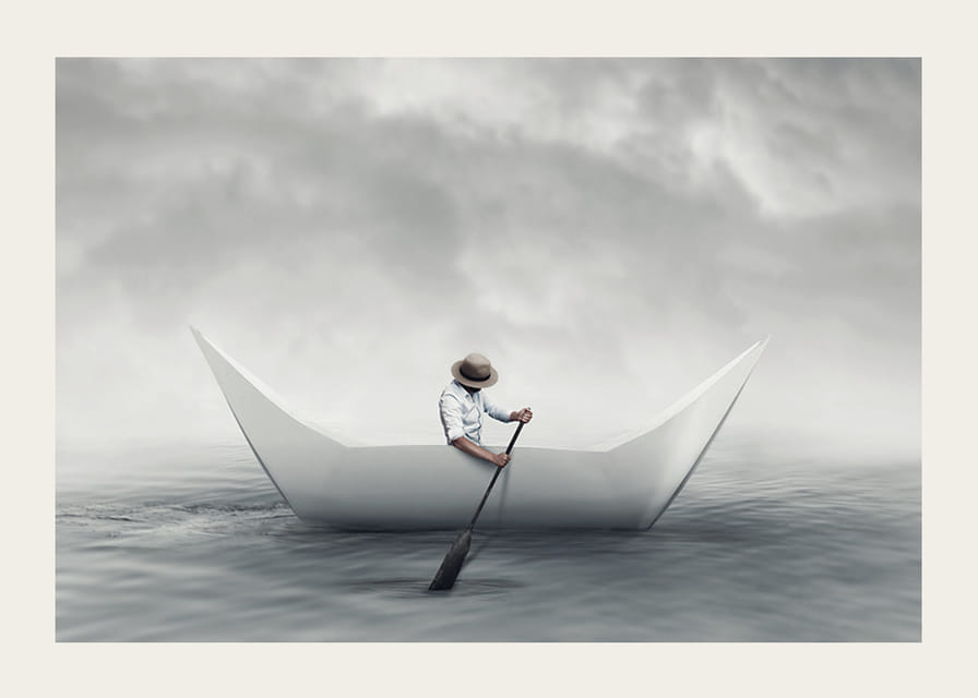 En drömlik scen där en man ror en pappersbåt över ett stilla hav-12