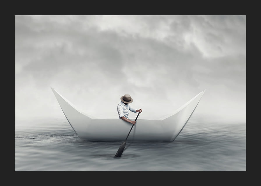En drömlik scen där en man ror en pappersbåt över ett stilla hav-12