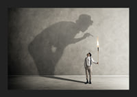 A symbolic image of facing one's inner demons, where a small torch casts a large, confrontational shadow-5