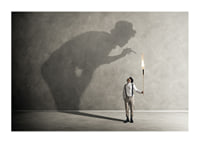 A symbolic image of facing one's inner demons, where a small torch casts a large, confrontational shadow-1