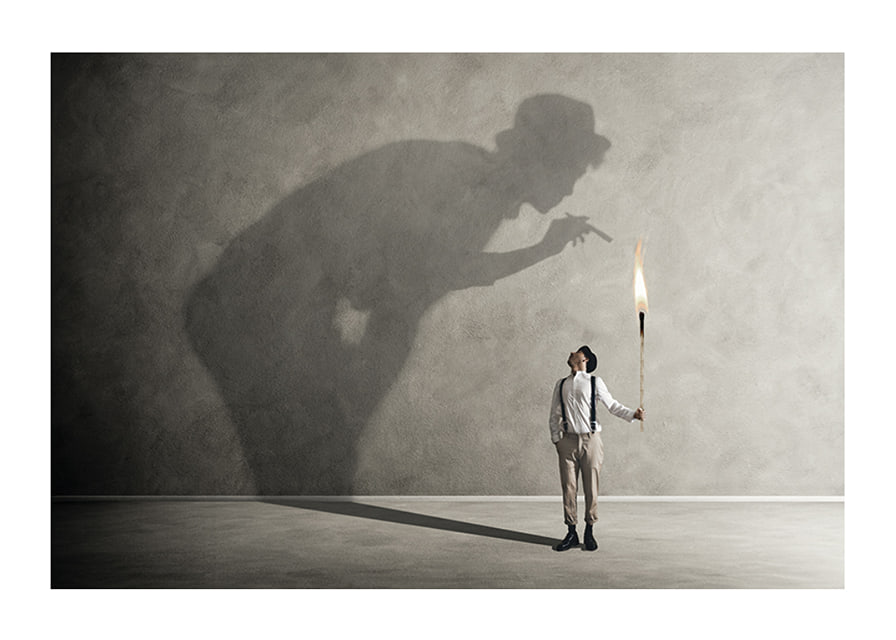A symbolic image of facing one's inner demons, where a small torch casts a large, confrontational shadow-12