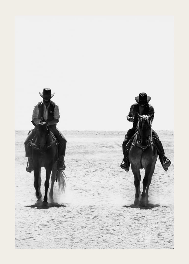 Två cowboys rider sida vid sida genom ett öde landskap, inramade av vilda västerns tidlösa mystik och frihet.-12