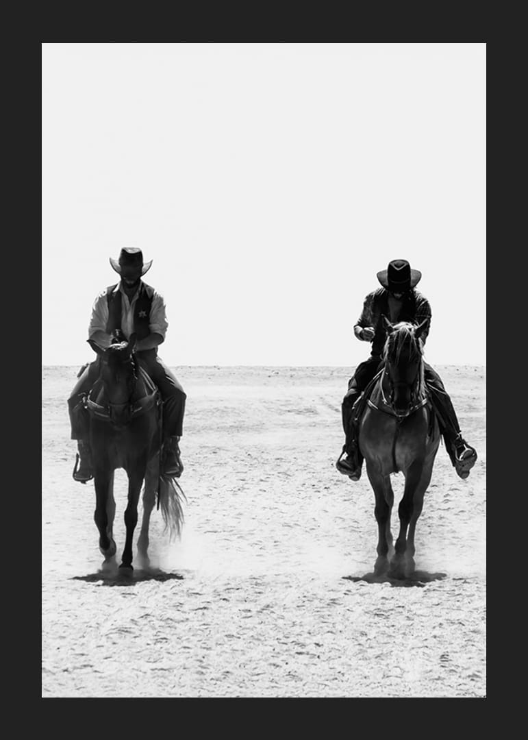 Två cowboys rider sida vid sida genom ett öde landskap, inramade av vilda västerns tidlösa mystik och frihet.-12