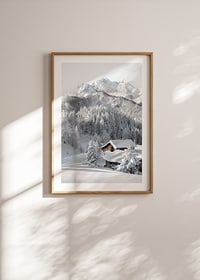 A snow-covered mountain cabin surrounded by frosty trees and majestic mountains that exudes winter idyll and tranquility.-8