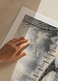 A snow-covered stone bridge spans a frozen stream in a still and magical winter landscape.-9