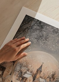 En juleplakat med en snekugle, der omslutter en malerisk, snedækket landsby i aftenlys.-9