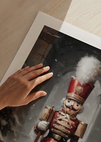 En juleplakat med en statelig Nøddeknækker i rød uniform omgivet af snedækkede grantræer.-9