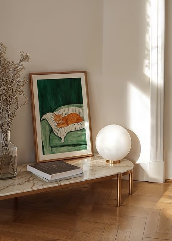 En plakat med en sovende orange kat på et stribet tæppe i en grøn lænestol-12