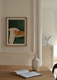 A poster of a sleeping orange tabby cat on a striped blanket in a green armchair-8
