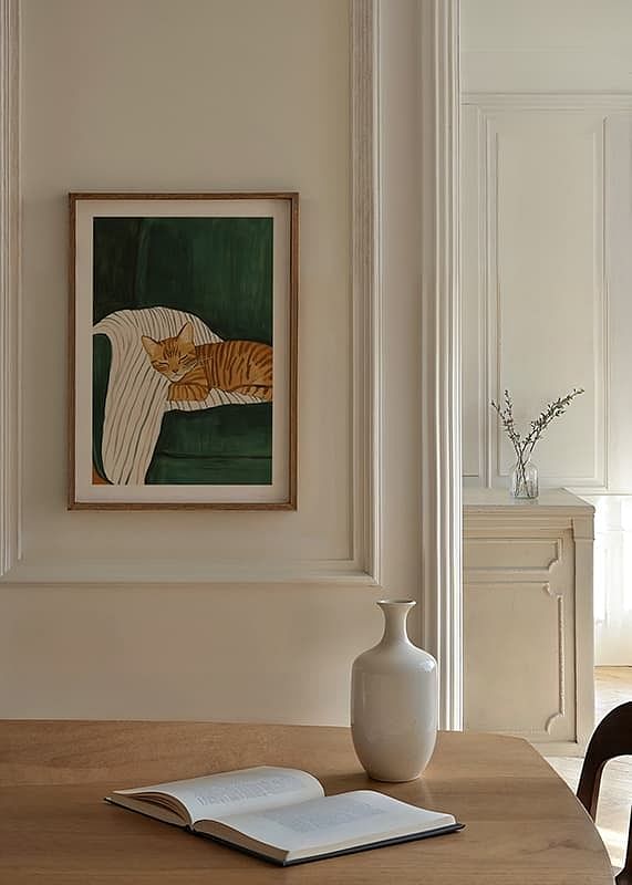 A poster of a sleeping orange tabby cat on a striped blanket in a green armchair-12