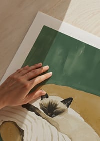A poster of a sleeping Siamese cat on a striped blanket in a brown armchair-9