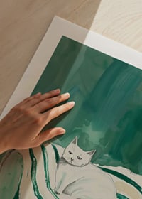 A poster of a white cat in a green armchair, giving the room a modern and artistic touch-9