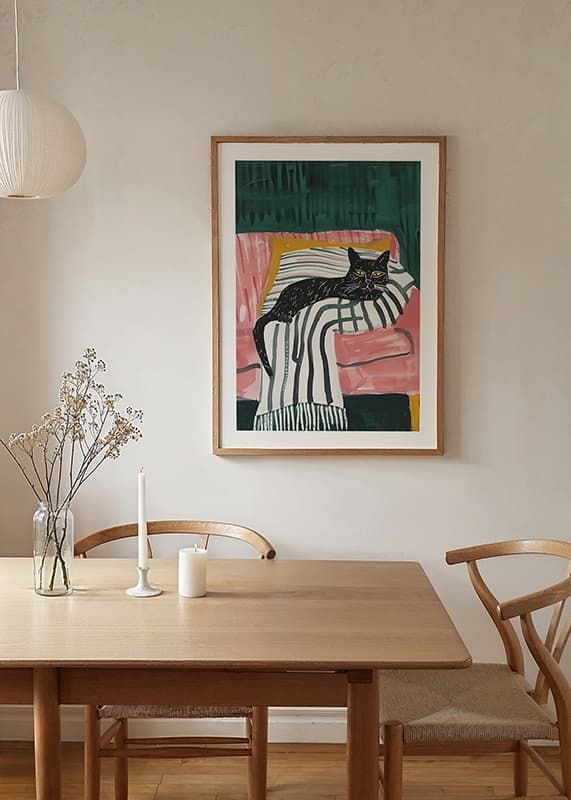 A poster of a black cat with golden eyes, resting on a striped blanket in a pink armchair-12