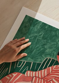 A poster depicting a relaxed figure in a patterned dress against a green-striped armchair-9