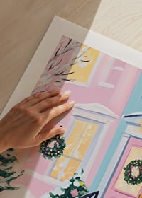En poster av en pastellfärgad ytterdörr dekorerad med julkransar och snötäckta buskar-9