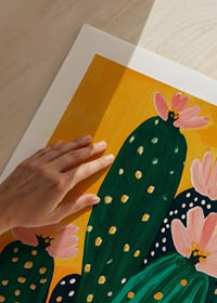 Colorful cactus blossom against a warm orange background spreads joy-9