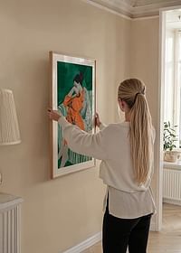 Een vrouw in oranje kleding leunt peinzend tegen een bank met een patroon-4